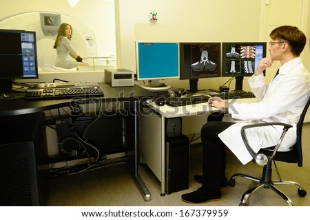 Young doctor sitting behind monitors in a computed tomography laboratory