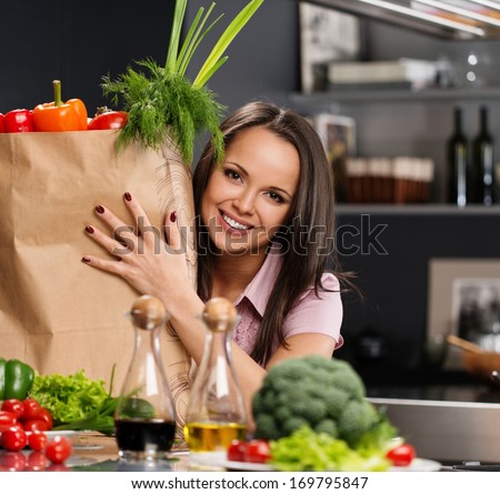 Young woman with grocery bag full of fresh vegetables on a modern kitchen