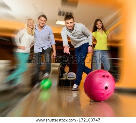 Group of four young smiling people playing bowling