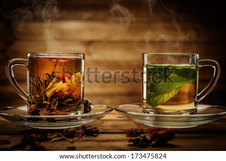Glass cups with tea flower and peppermint tea against wooden background
