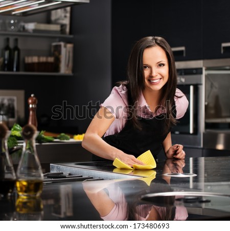 Young cheerful woman cleaning modern kitchen