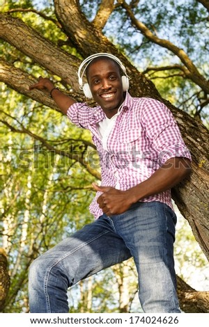 Positive young african american man listens music in a park