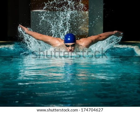 Muscular young man in blue cap in swimming pool