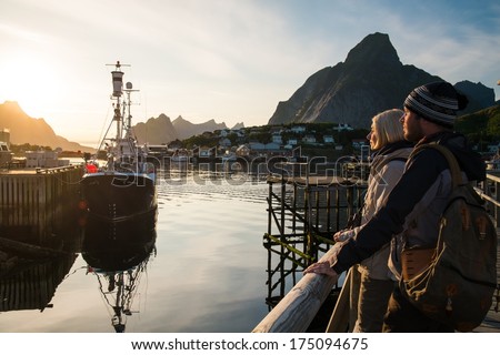 Young travellers couple looking at sunset in Reine village, Norway