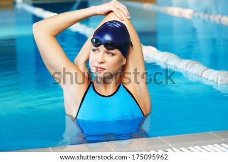 Young woman wearing blue swimming suit and cap in swimming pool