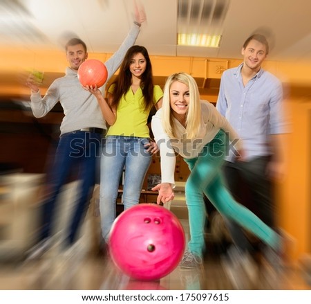 Group Of Four Young Smiling People Playing Bowling