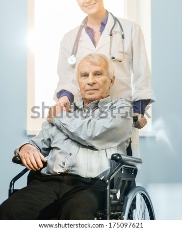 Cheerful young nurse woman with senior man in wheelchair