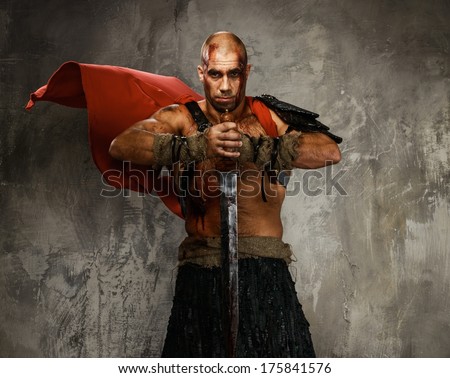 Wounded gladiator with  sword covered in blood isolated on grey