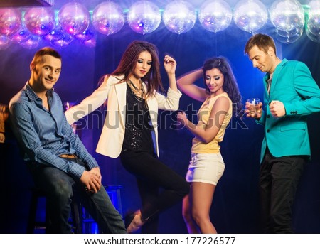 Group of happy young people dancing at night club