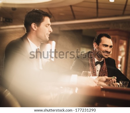 Two Young Men In Suits Behind Gambling Table In A Casino