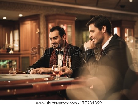 Two young men in suits behind gambling table in a casino