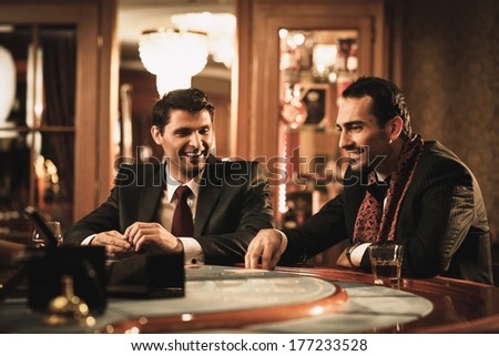 Two young men in suits behind gambling table in a casino
