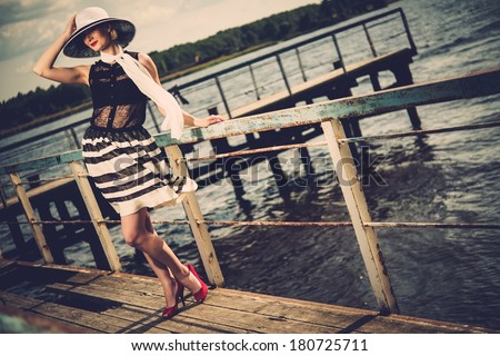 Woman in white hat and scarf standing near old pier rails