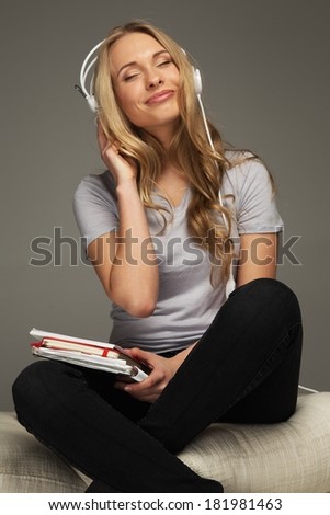 Positive young woman student with notebook listens to music