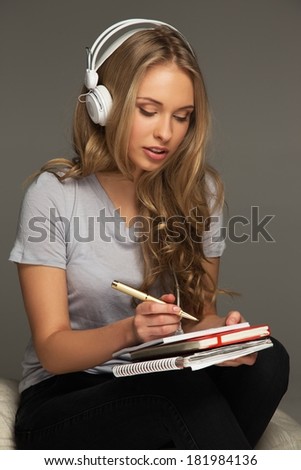 Young woman student with notebook listens to music