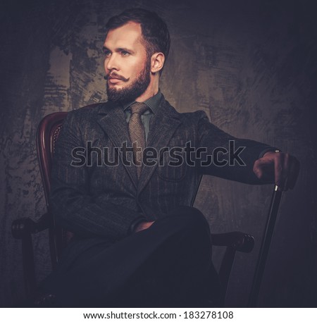 Handsome well-dressed with stick sitting in leather chair