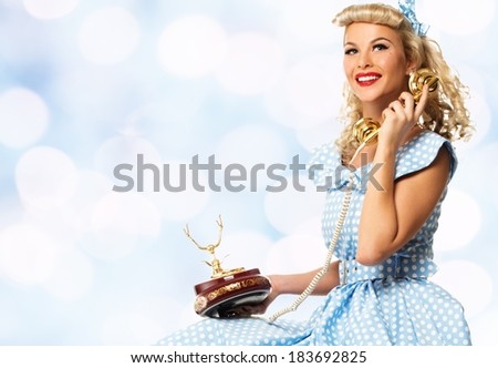 Coquette blond pin up style young woman in blue dress with vintage phone