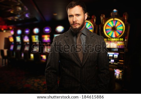 Handsome well-dressed man against slot machines in a casino