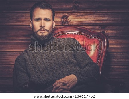 Handsome man wearing cardigan in wooden rural house interior