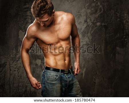 Young man with muscular  body in blue jeans
