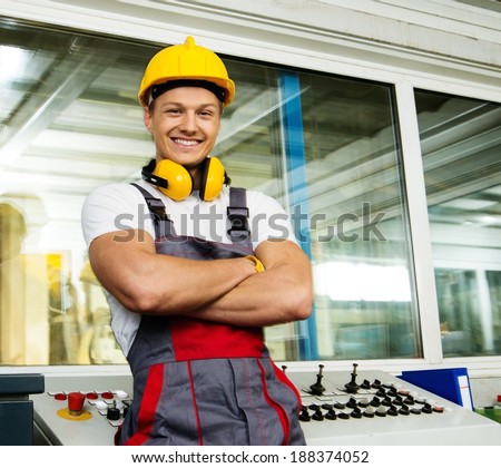 Happy worker wearing safety hat in a factory control room Happy worker wearing safety hat in a factory control room