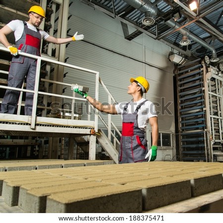 Worker and foreman in a safety hats performing quality check on a factory