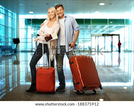 Happy couple with suitcases and map in airport