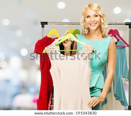 Smiling blond woman choosing clothes on a rack in a shopping mall