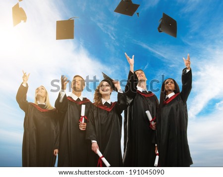 Happy multi ethnic group of graduated young students throwing hats in the air