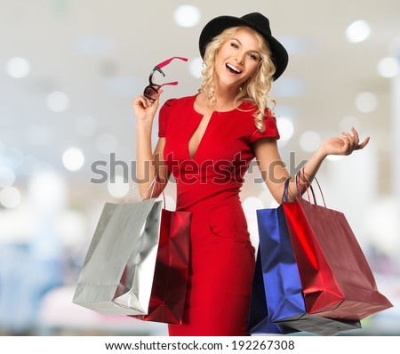 Smiling young blond woman with shopping bags in shop interior