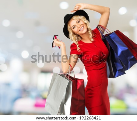 Smiling young blond woman with shopping bags in shop interior