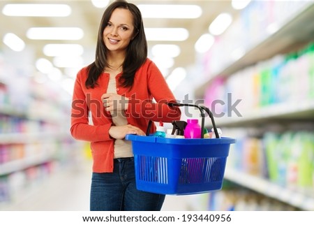 Beautiful cheerful brunette woman with basket full of cleansers in a shop