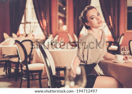 Beautiful young woman with cup of coffee alone in a restaurant
