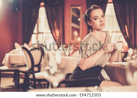 Beautiful young woman with cup of coffee alone in a restaurant