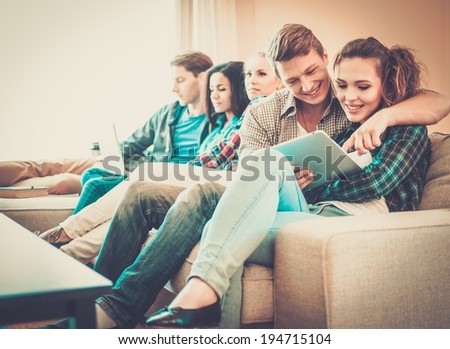 Group of students with tablet pc and laptop preparing for exams in apartment interior