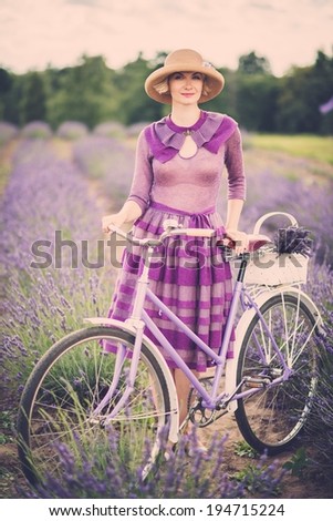Woman in purple dress and hat with retro bicycle in lavender field