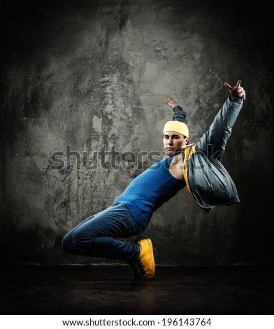 Man dancer in cap and jacket showing break-dancing moves