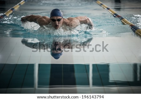 Young man in swimming cap and goggles swim using breaststroke technique