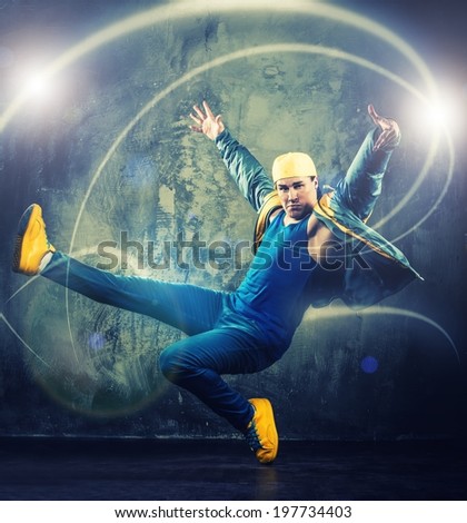 Stylish man dancer showing break-dancing moves with magic beams around him