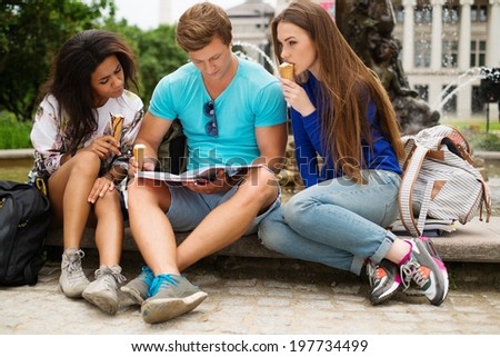 Group of multi ethnic students with ice-cream near fountain in a city park