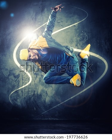 Stylish man dancer showing break-dancing moves with magic beams around him