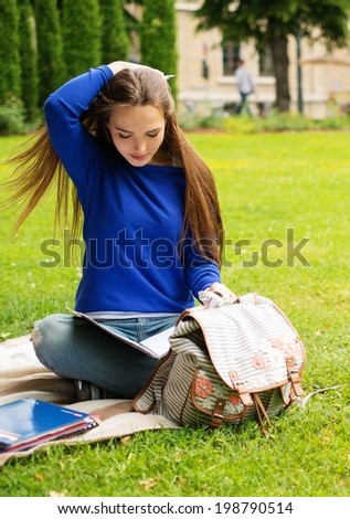 Beautiful young student girl in a city park on summer day