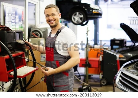 Serviceman with co/hc diagnostic tool in a car workshop