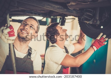 Servicemen checking suspension in a car workshop