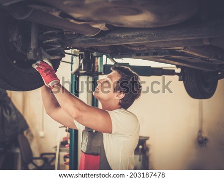 Serviceman checking suspension in a car workshop