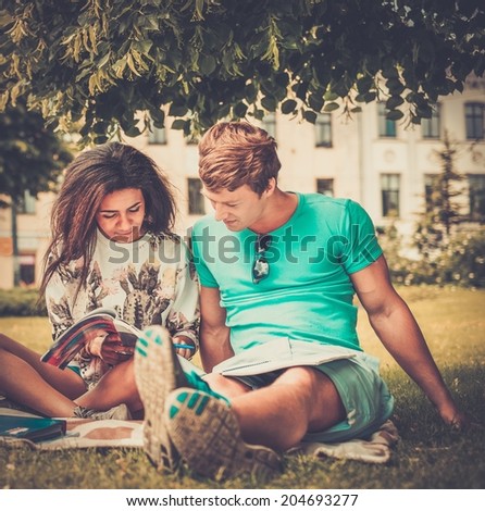 Multi ethnic students couple preparing for final exams in a city park