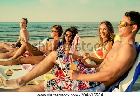 Group of multi ethnic friends sunbathing on a deck chairs on a beach