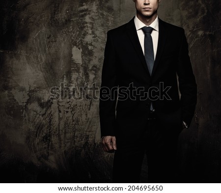 Well-dressed man in black suit against grunge wall