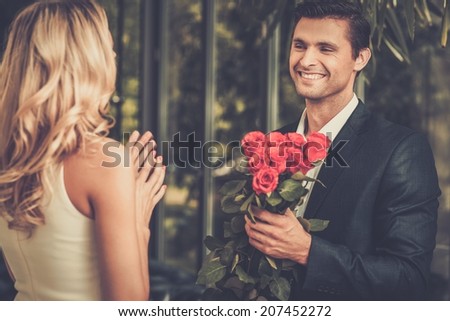 Handsome man with bunch of red roses dating his lady
