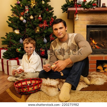 Young father with his son near fireplace in Christmas decorated house interior